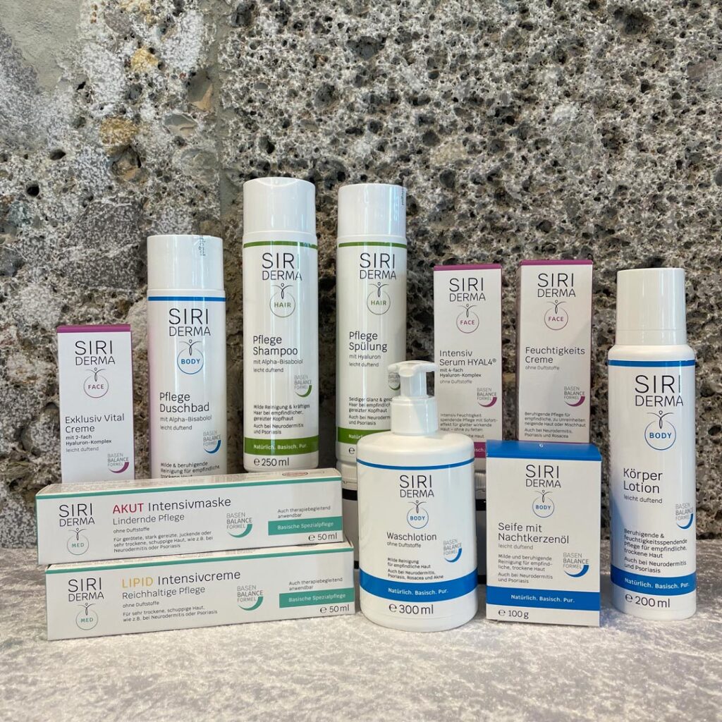 Verschiedene Apotheken-Produkte in unterschiedlichen Verpackungen und Größen, angeordnet auf einer Marmoroberfläche vor einem grauen Stein-Hintergrund.